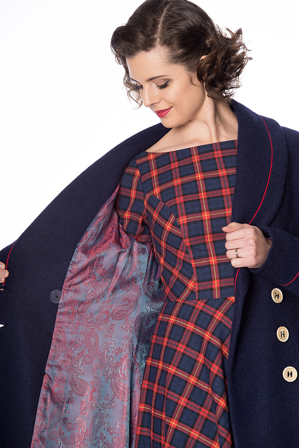 Retro model in navy long line coat with orange piping and buttons showing paisley lining