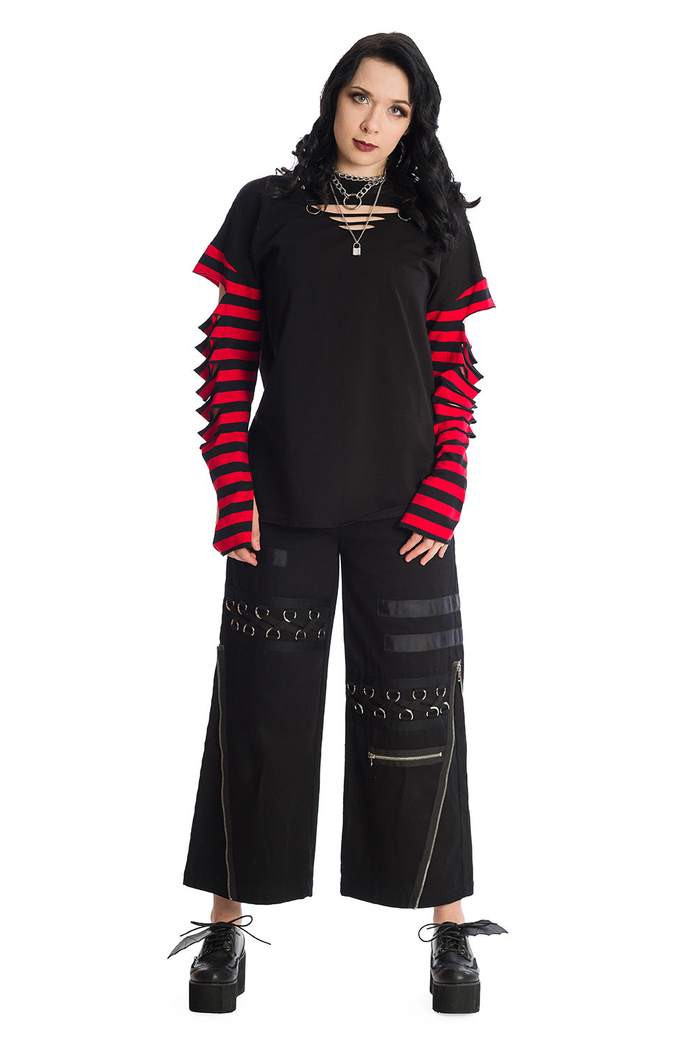 Model wearing Baggy black trousers with zip and buckle features with a long sleeved striped red top with rips