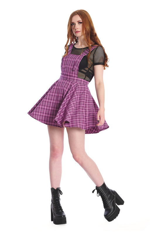 Model in a purple pinafore dress with black mesh crop top and black boots