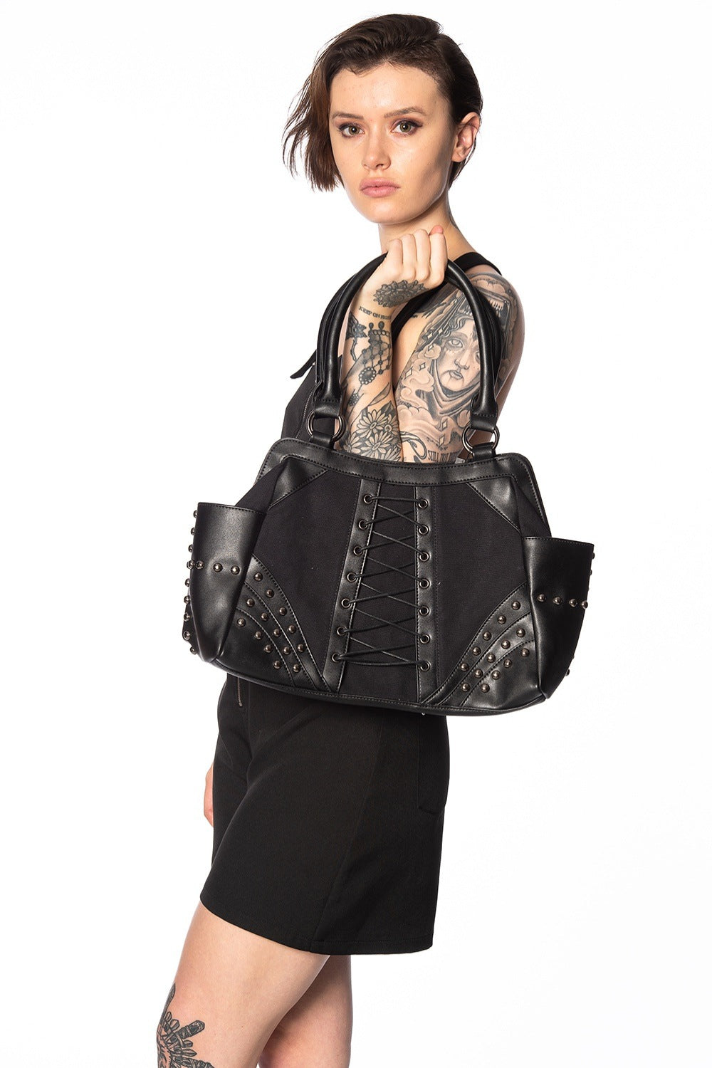 Alternative model holding black corset detail handbag with studs