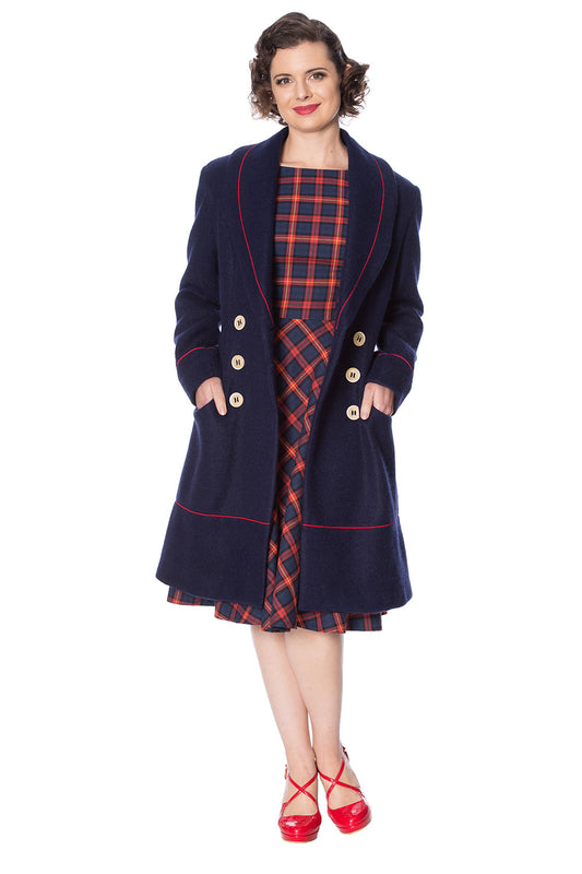 Retro model in navy long line coat with orange piping and buttons