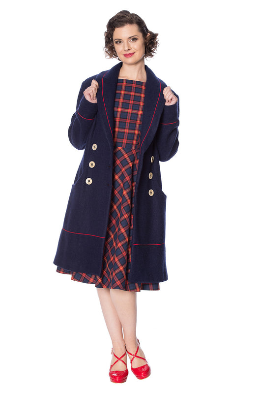 Retro model in navy long line coat with orange piping and buttons