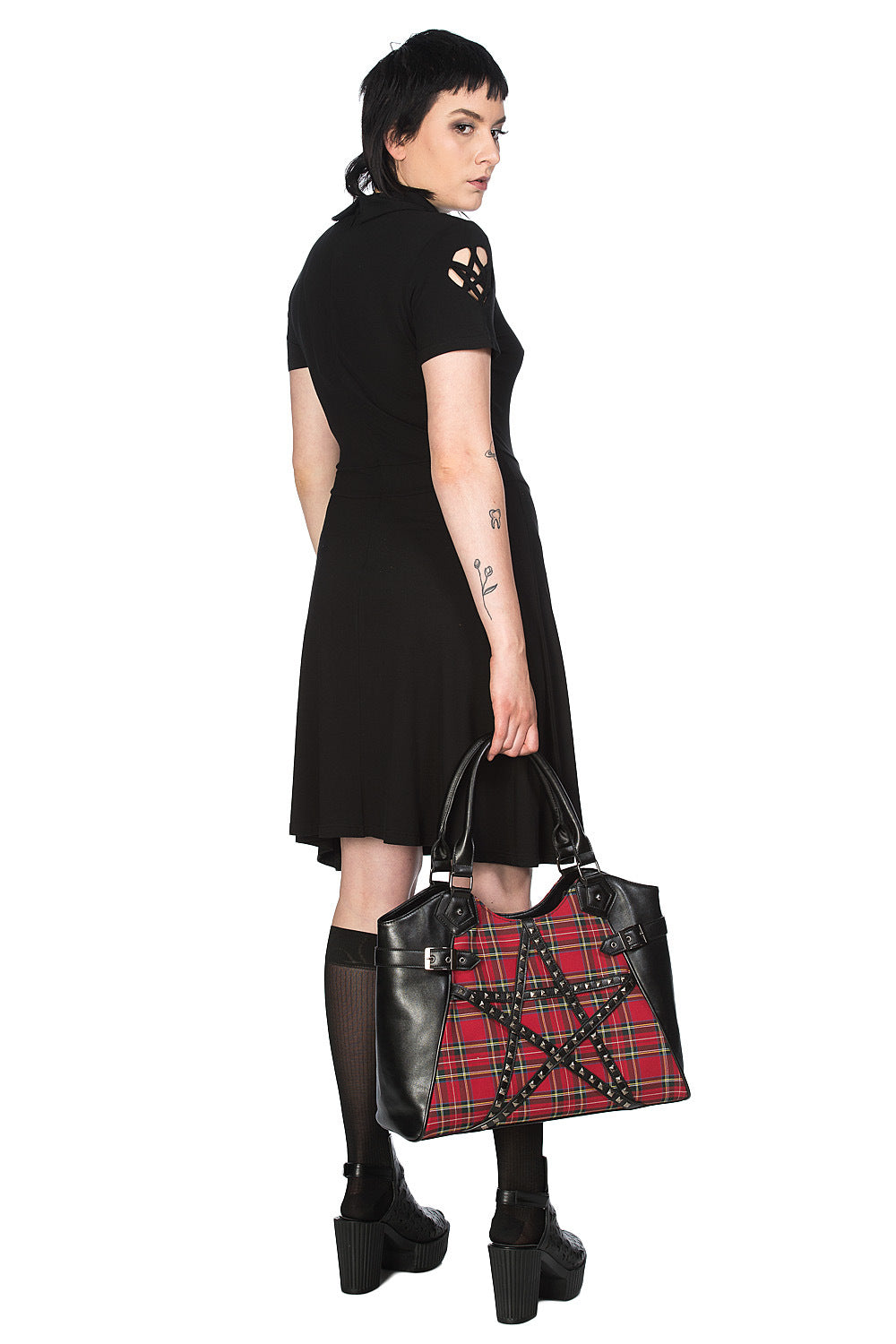 Alternative model in black dress holding red tartan hand bag with studded pentagram