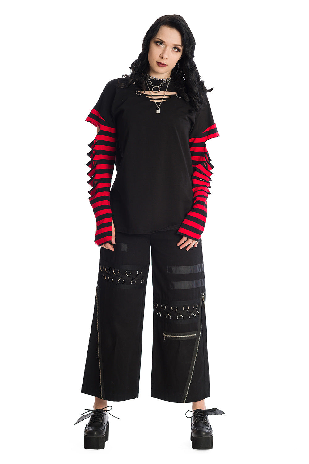 Model wearing Baggy black trousers with zip and buckle features with a long sleeved striped red top with rips 