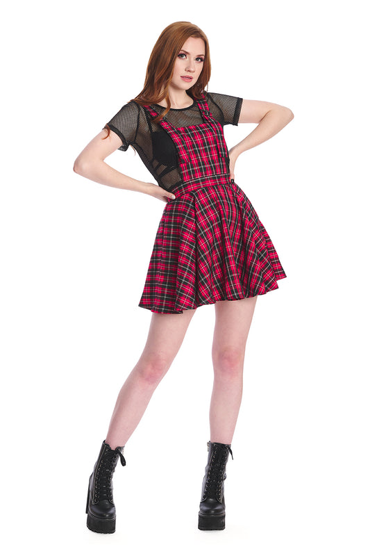 Model in a red pinafore dress with black mesh crop top and black boots 