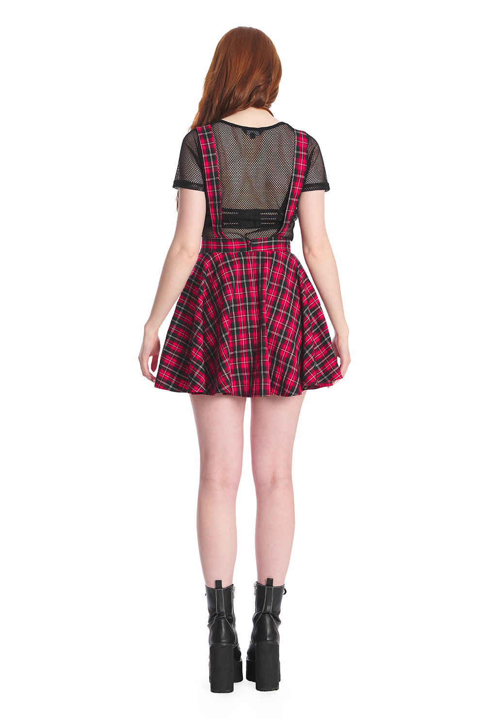 Model in a red pinafore dress with black mesh crop top and black boots 