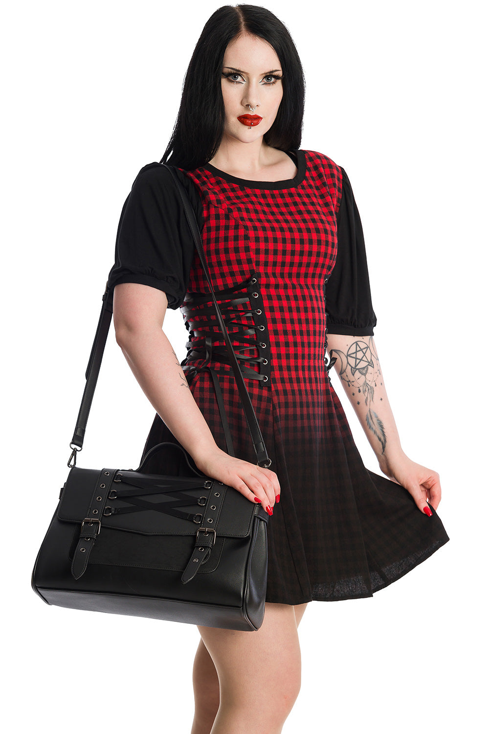 Alternative model in red check dress holding Black corset detailed handbag with buckles