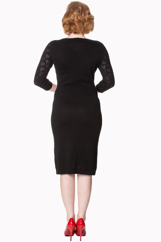 Model wearing black mid length fitted dress with sheer pattern sleeves