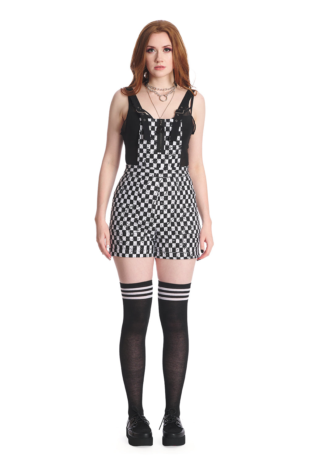 Model in a black and white checkerboard playsuit with thigh high socks